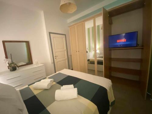 a room with a television and a bed with towels at Home Romana Centro Nettuno in Nettuno