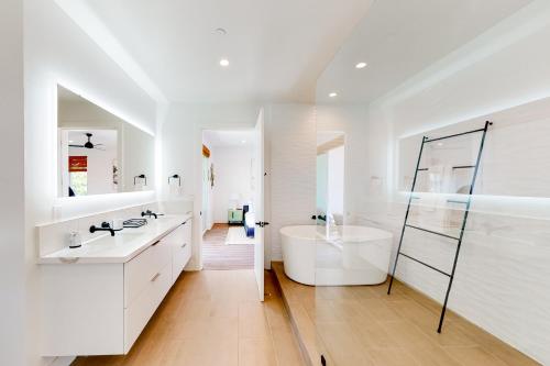 a white bathroom with a tub and a sink at Seaside Serenity Retreat Inviting condo in Oceanside with rooftop, hot tub, balcony, and ocean views in Oceanside