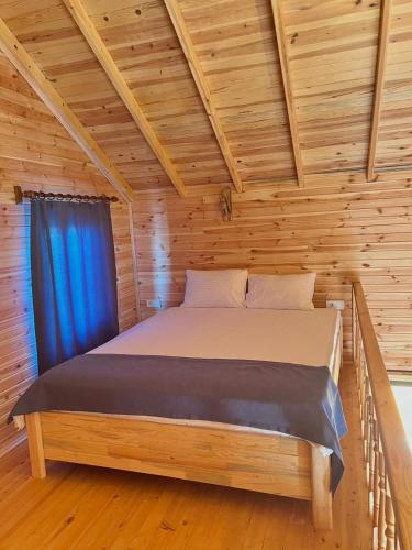a bed in a log cabin with a blue curtain at lemon garden bungalow in Demre