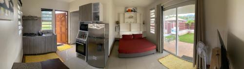 Il comprend une cuisine équipée d'un réfrigérateur en acier inoxydable et une fenêtre. dans l'établissement Jorsen House Tahiti 2 : bungalow confortable, à Taravao