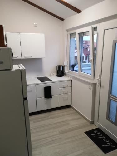 a kitchen with white cabinets and a stove top oven at Apartman The View Krk in Krk