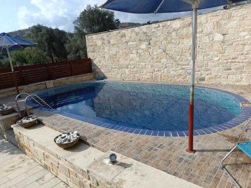 a large swimming pool with an umbrella and an umbrella at Petrini Villa with swimming pool in Kapparianá