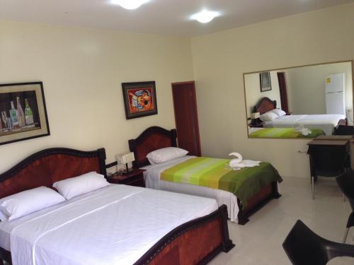 a hotel room with two beds and a mirror at Hotel MundialCity in Guayaquil