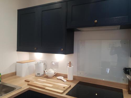a kitchen with black cabinets and a counter top at The Creek-Stone Den in Oban