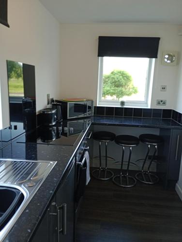 a kitchen with black counter tops and bar stools at Station Retreat in Boldon