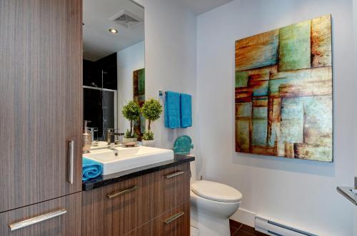ein Badezimmer mit einem Waschbecken, einem WC und einem Gemälde in der Unterkunft Les Immeubles Charlevoix - Le 760406 in Québec