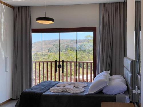 a bedroom with a bed with a view of a balcony at Serra dos encantos in Lavras Novas