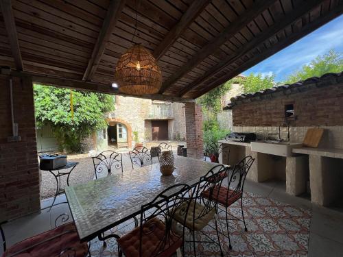 un patio avec une table et des chaises et une cuisine dans l'établissement Magnanerie avec piscine en Coeur de village, à Canaules-et-Argentières