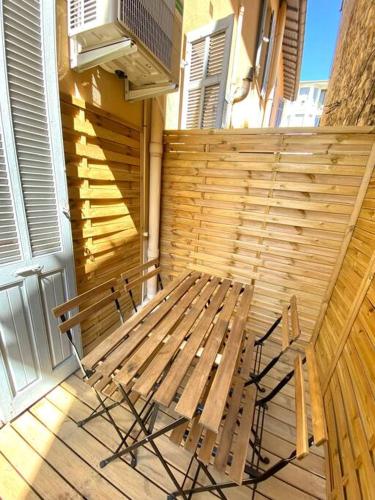 un banc en bois installé sur une terrasse couverte avec un balcon dans l'établissement Cosy apartment in Cannes with a terrasse, à Cannes