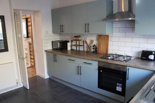 cocina con armarios blancos y fogones en Stylish & Comfortable House in Swansea, en Morriston