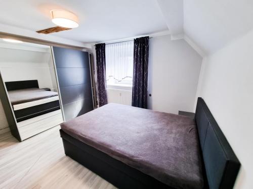 Dormitorio pequeño con cama y espejo en Da Vinci Appartement, en Kapfenberg