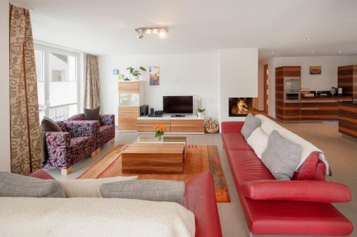 a living room with a red couch and a fireplace at Haus Powder Snow in Zermatt