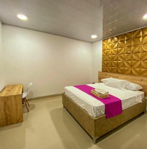 a bedroom with a large bed and a table at HOTEL VIOLETTA Cereté in Cereté