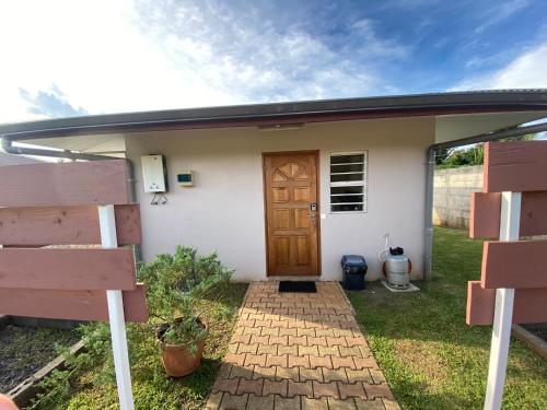 une petite maison blanche avec une porte en bois dans l'établissement Jorsen House Tahiti 2 : bungalow confortable, à Taravao