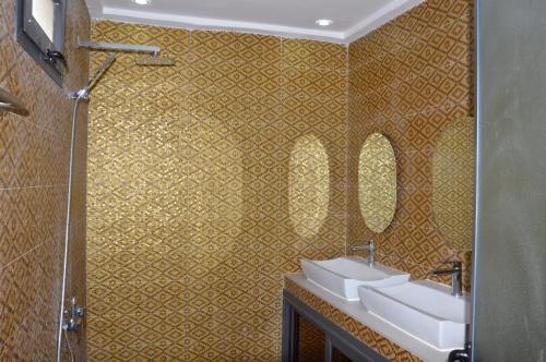 a bathroom with two sinks and two mirrors at Keur Méry in Ngaparou