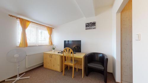 a room with a desk with a computer and a chair at Penzion Pod kolem in Šošŭvka