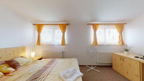 a bedroom with a large bed and two windows at Penzion Pod kolem in Šošŭvka