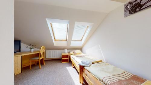 a bedroom with two beds and a desk and a window at Penzion Pod kolem in Šošŭvka