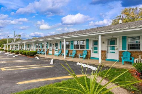 伊利的住宿－Riviera Motel，停车场内有蓝色椅子的建筑