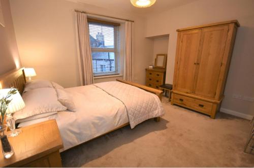 a bedroom with a bed and a dresser and a window at Snug on the Tweed in Berwick-Upon-Tweed