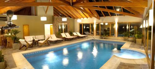 a swimming pool in a house with chairs and tables at Chamonix Posada & Spa in Villa General Belgrano