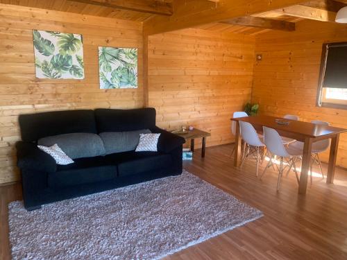 a living room with a black couch and a table at Moinho de Vento (CASA DE MADEIRA) in Castelo Branco