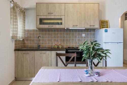 a kitchen with a table and a white refrigerator at Elios Cozy Apartment in Neo Klima