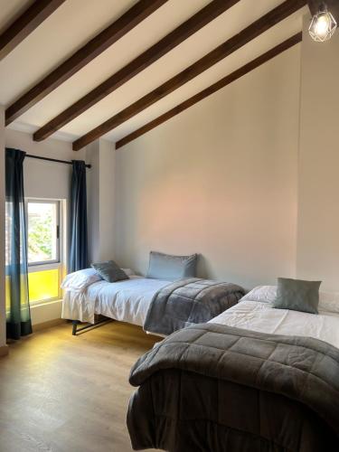 two beds in a room with a ceiling with beams at Casa en Treceño 5 Dormitorios y 2 Plantas in Treceño