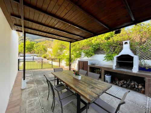 an outdoor patio with a wooden table and chairs at Villa en Frigiliana con Piscina y Jacuzzi in Frigiliana