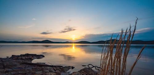a sunset on a lake with the sun setting at Hickory Bear - Cabin surrounded by pines, Sleeps 10, Hot Tub, Fire Pit, Arcade, Foosball Table & Deck Slide in Broken Bow
