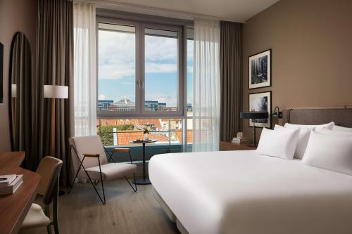 a hotel room with a large white bed and a desk at NH Collection Heidelberg in Heidelberg