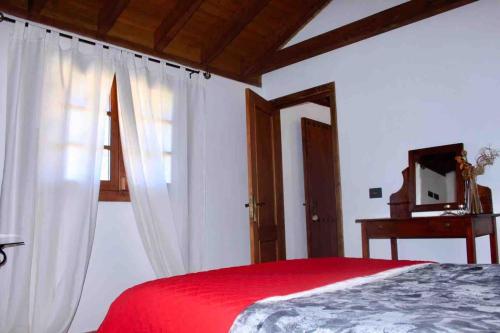 a bedroom with a red bed and a mirror at Casa Matilde in Hermigua