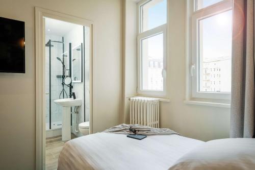 a bedroom with a bed and a sink and two windows at Best Western Metz Centre Gare in Metz