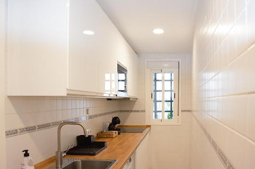 cocina blanca con fregadero y ventana en Exclusivo Apartamento en el Centro de Sevilla, en Sevilla