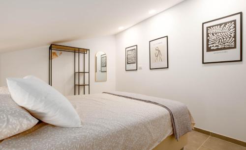 a white bedroom with a bed and pictures on the wall at Apartment Eros in Šišan