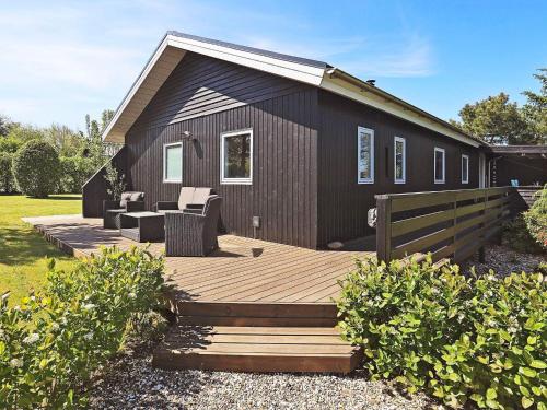 a wooden deck with chairs and a house at 4 person holiday home in Vinderup-By Traum in Vinderup