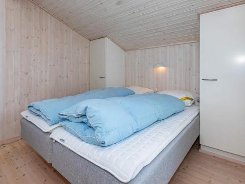 uma grande cama azul num quarto com paredes de madeira em Holiday home Løgstør XXIV em Løgsted