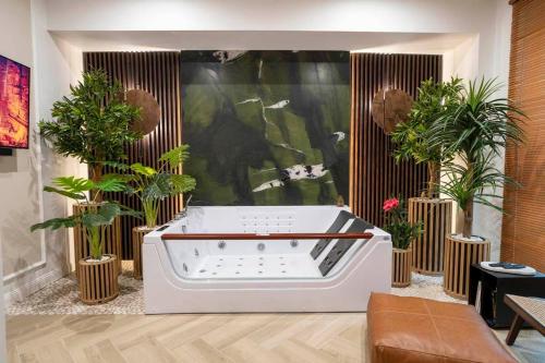 a bath tub in a room with potted plants at Aparthotel ZATOR Retro 66 jacuzzi in Zator