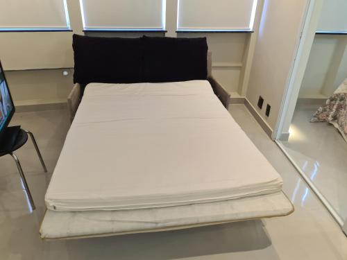 a large white bed with a black pillow on a floor at Apartamento na Barra da Tijuca in Rio de Janeiro