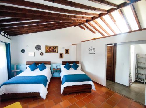 a bedroom with two beds with blue and white sheets at Casa El Retiro - Villa de Leyva in Villa de Leyva
