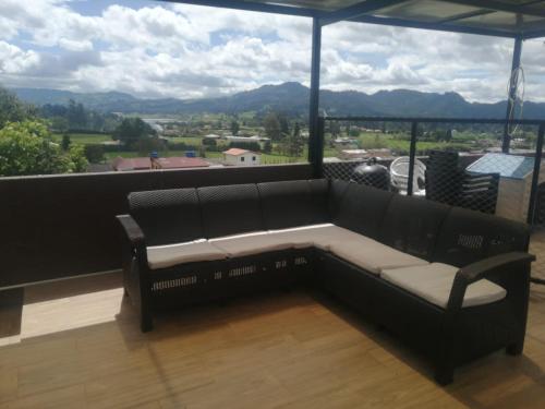 un sofá en un balcón con vistas a las montañas en Hospedaje Miguel Ángel, en Tabio