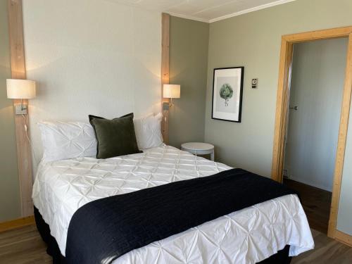 a bedroom with a bed with a black and white comforter at Hôtel-Motel Vagues Vertes in Perce