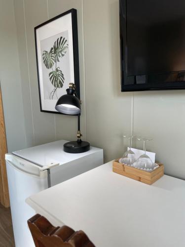 a white table with a lamp and a television on a wall at Hôtel-Motel Vagues Vertes in Perce
