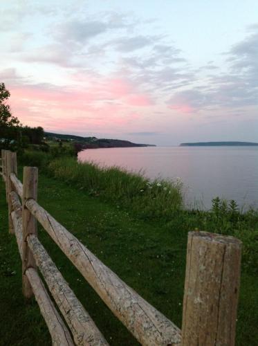 a wooden fence next to a body of water at Hôtel-Motel Vagues Vertes in Perce