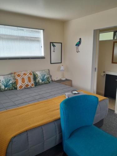 Sunset Accommodation في ويستبورت: غرفة نوم بسرير وكرسي ازرق