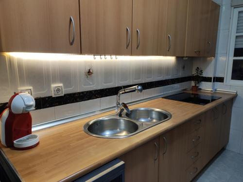 a kitchen with a stainless steel sink and wooden cabinets at Entre la Alhambra y Sierra Nevada in Cenes de la Vega