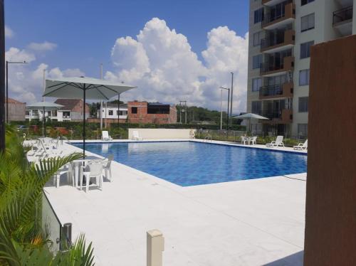 a swimming pool with white chairs and an umbrella at PEÑALISA in Ricaurte