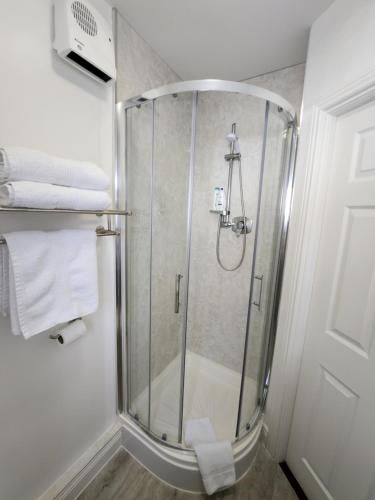 a shower with a glass door in a bathroom at Park View room with free minibar tea&coffee in Dublin