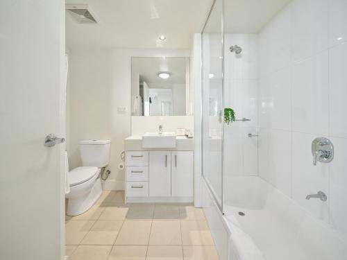 a white bathroom with a toilet and a shower at Quest Breakfast Creek in Brisbane