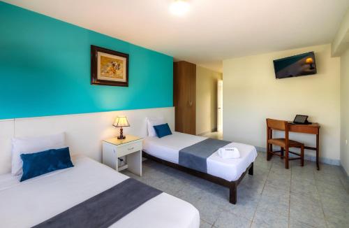 a hotel room with two beds and a desk at Hotel Country Trujillo in Trujillo